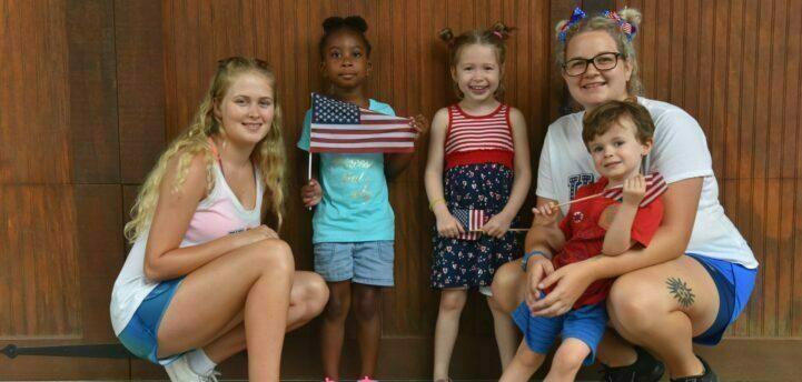 Four children posing together, two holding American flags.