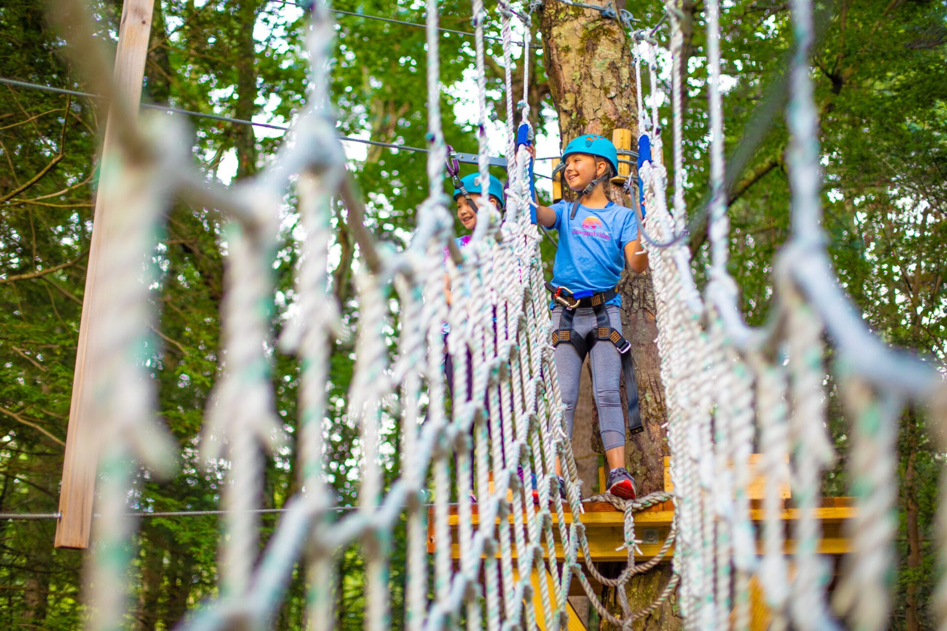 Child navigating a rope bridge in an adventure park.