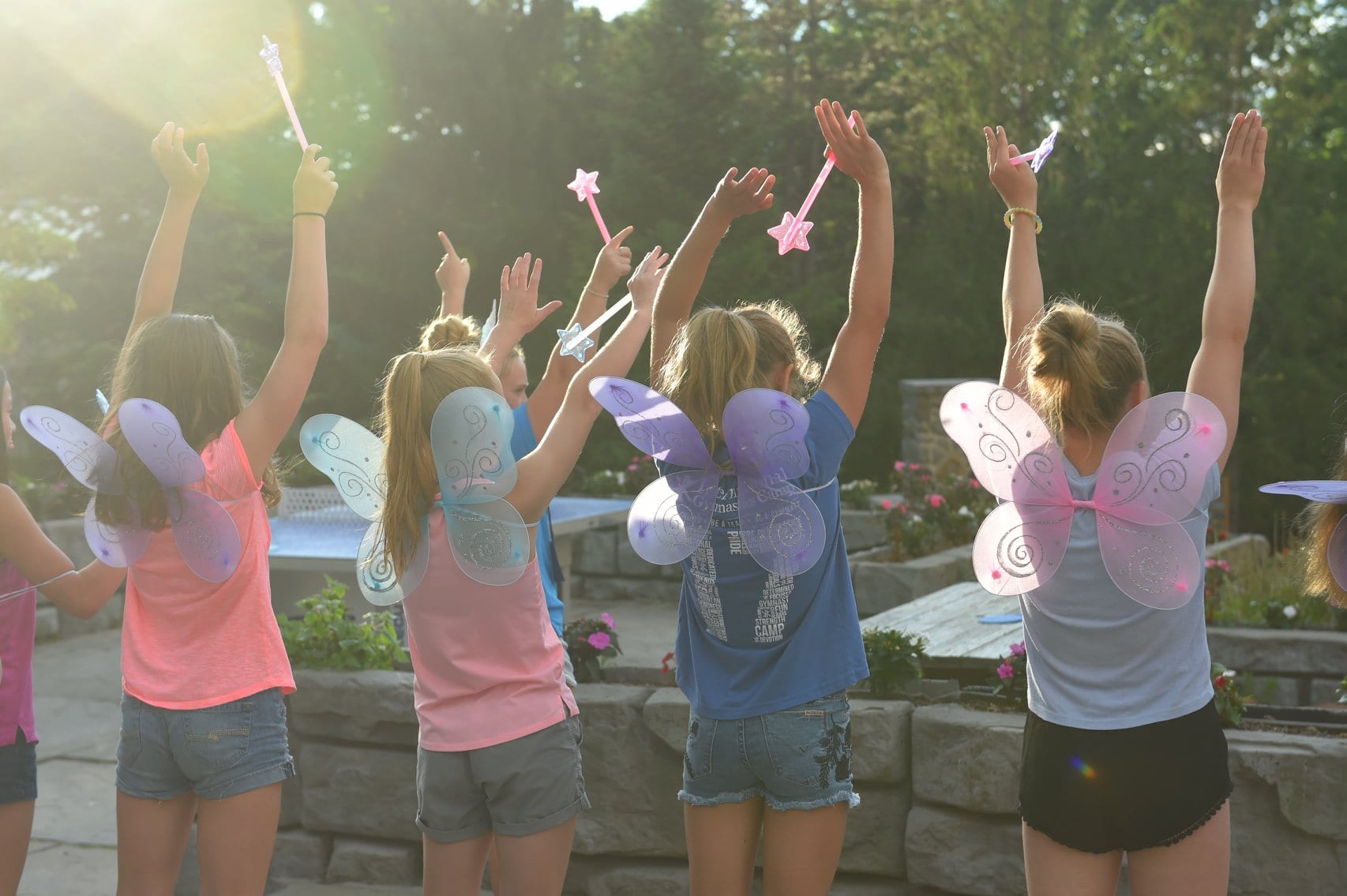 A group of girls outdoors holding up star-shaped lights at sunset.