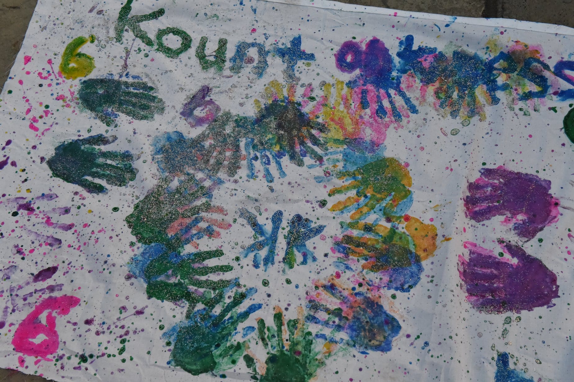 Colorful handprints and the phrase 'Kunst gibt' on a white surface.