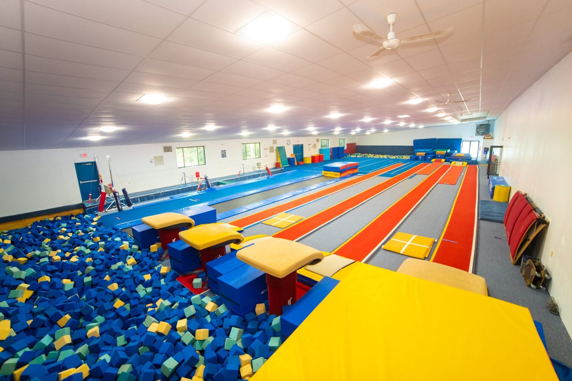Indoor gymnastics facility with foam pit and various apparatuses.